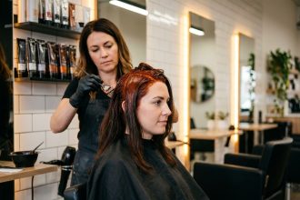 Femme en salon de coiffure recevant une coloration cuivrée appliquée par une coloriste professionnelle