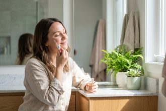 Femme appliquant un serum visage dans une salle lumineuse